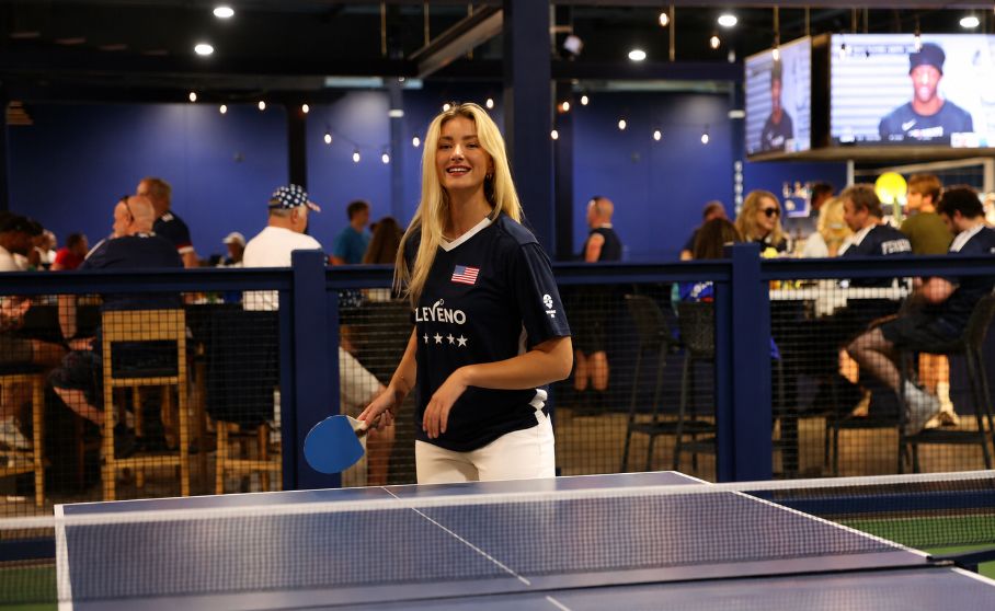 An ELEVENO member with her paddle beside the indoor courts, the bar behind her