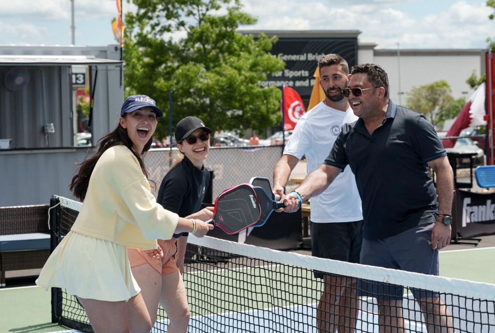 Four players meeting at the net on an outdoor court
